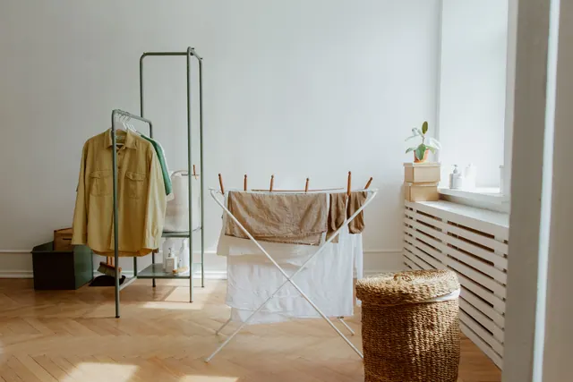 Tendedero con ropa colgada en el salón de una vivienda
