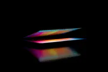 Un ordenador portátil entreabierto iluminado con luces de colores