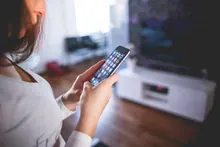Una mujer usa un teléfono móvil en un salón de casa