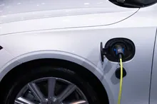 Coche eléctrico blanco cargando con un cable conectado a la carrocería