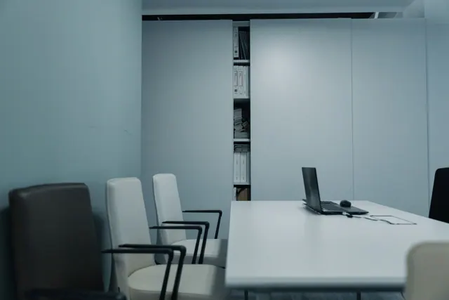 Sala de reuniones vacía con mesa, sillas y un portátil