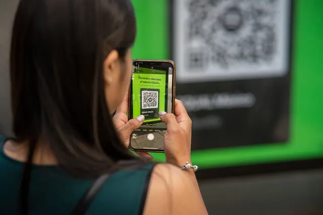 Teléfono móvil sobre una mesa junto a una entrada de papel y unos auriculares