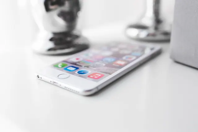 Un teléfono móvil sobre una mesa junto a objetos decorativos