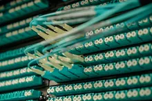 Pasillo de un centro de datos con armarios de servidores y haces de cables de fibra óptica