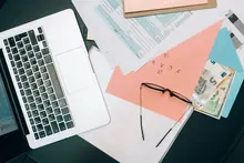Mesa de oficina de una pequeña empresa con portátil, carpetas y lámpara
