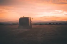 Una maquinaria agrícola trabajando en un campo al atardecer