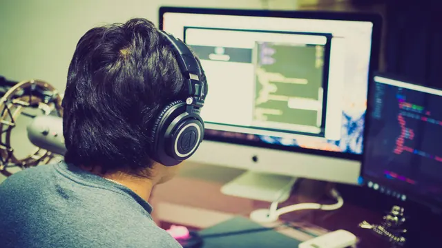 Puesto de trabajo con dos monitores, teclado y cuaderno en una oficina de desarrollo de software