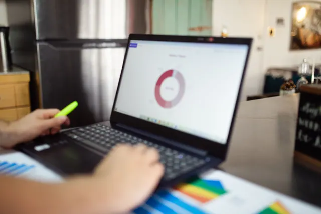 Una persona trabaja con un portátil mostrando un gráfico circular