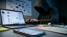 Una persona con capucha utiliza un portátil mientras trabaja en un escritorio