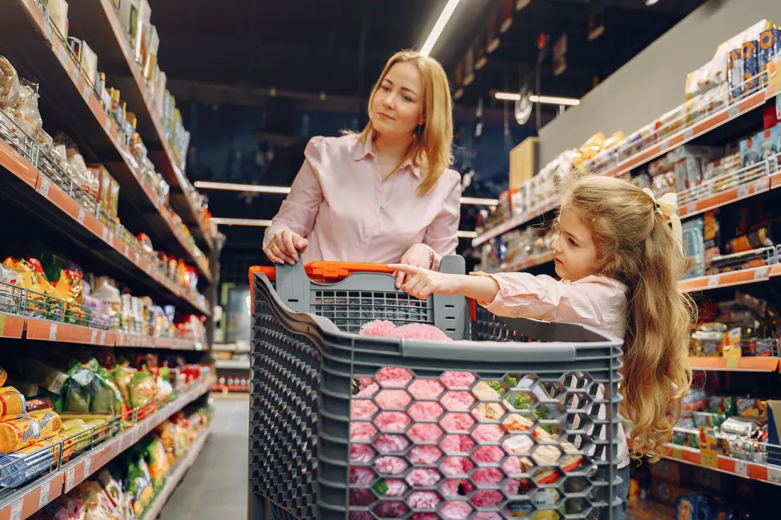Una madre y su hija con un carrito en el pasillo de un supermercado