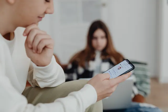Adolescente deslizando el dedo por la pantalla del móvil en penumbra