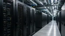 Centro de datos con racks de servidores negros alineados en pasillo iluminado