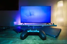 Mando de videoconsola sobre una mesa frente a un televisor encendido