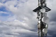 Torre de telecomunicaciones con antenas parabólicas bajo un cielo nublado