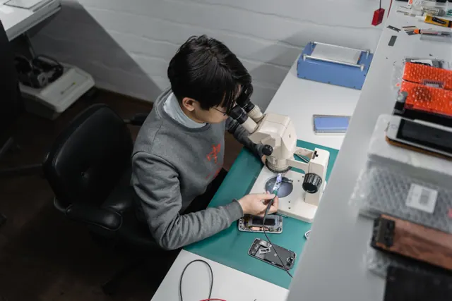 Técnico reparando un iPhone antiguo abierto sobre una mesa de taller
