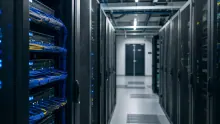 Centro de datos con servidores negros y cables azules en pasillo iluminado