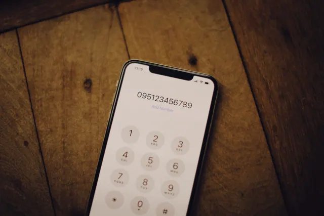 Teléfono móvil básico con teclado físico apoyado sobre una mesa de madera
