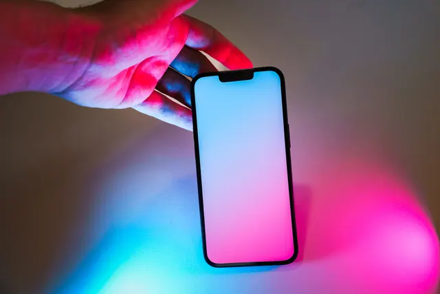 Una mano sostiene un teléfono móvil iluminado con luces de colores