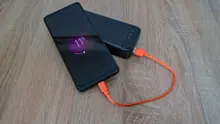 Un teléfono móvil cargándose con una batería portátil sobre una mesa