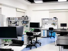 Laboratorio moderno con estaciones de trabajo, monitores apagados y sillas vacías