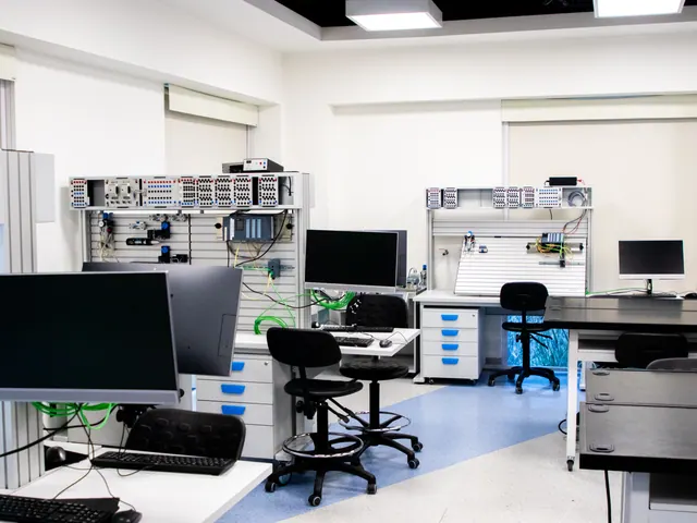 Laboratorio moderno con estaciones de trabajo, monitores apagados y sillas vacías
