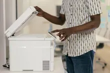Escáner de documentos compacto sobre una mesa de oficina con hojas de papel