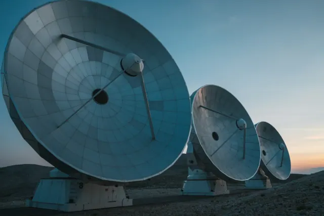 Antenas de radiotelescopio en un desierto al atardecer