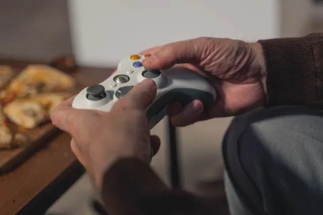 Jugador con mando de videoconsola frente a una televisión en el salón de casa