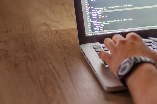 Persona programando en un portátil con código JavaScript en pantalla