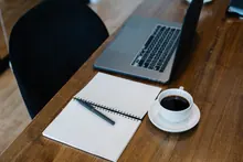Escritorio de madera con portátil, cuaderno y taza de café