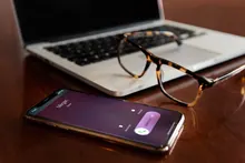 Teléfono móvil sobre una mesa de madera junto a una libreta y una taza
