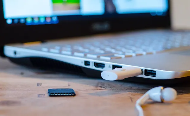 Conversor de audio USB con cable y auriculares sobre una mesa de escritorio