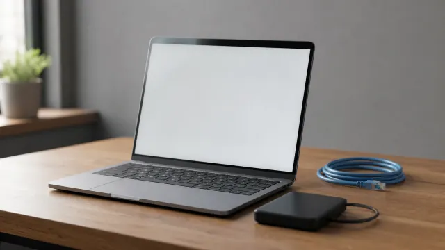 Portátil con pantalla en blanco sobre escritorio de madera junto a disco duro externo