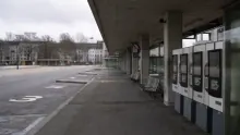 Andén de estación con máquinas expendedoras y plaza urbana al fondo