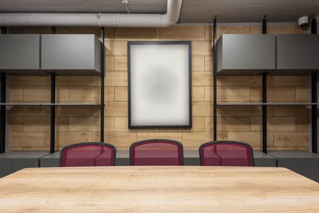 Sala de reuniones vacía con mesa de madera y sillas rojas