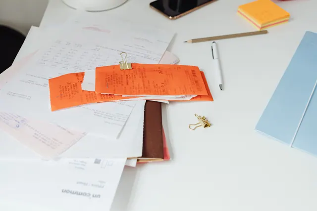 Escritorio con recibos, papeles y material de oficina