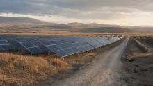 Huerto solar con paneles fotovoltaicos en terreno árido con montañas al fondo