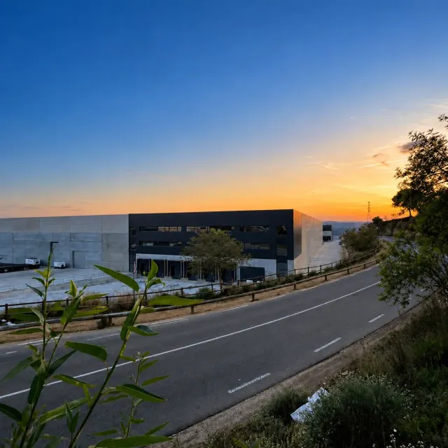 Nave industrial junto a una carretera al atardecer