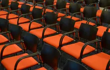 Filas de sillas vacías con asientos naranjas en una sala