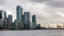 Skyline de rascacielos junto a un puerto fluvial con grúas de carga