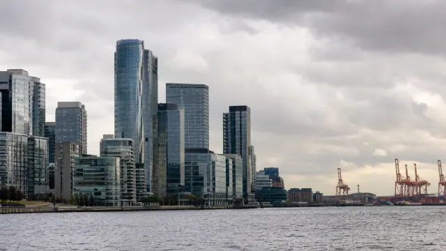 Skyline de rascacielos junto a un puerto fluvial con grúas de carga