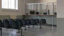 Varias sillas negras en una sala de espera con divisiones de vidrio y ventanas