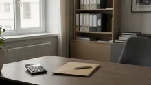 Escritorio de oficina con calculadora, bloc de notas y bolígrafo junto a ventana