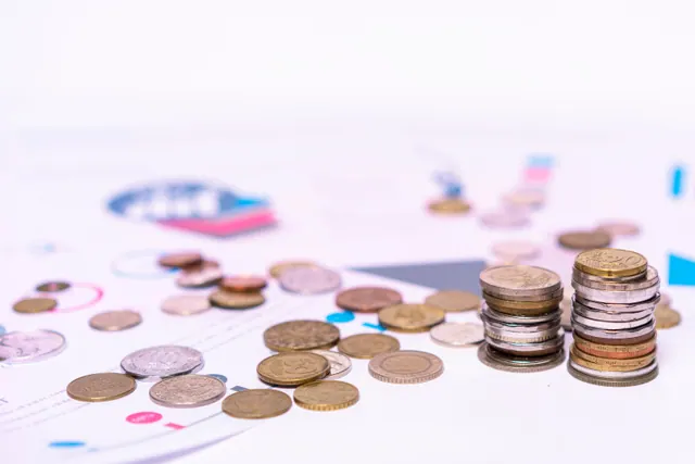 Monedas apiladas sobre gráficos financieros