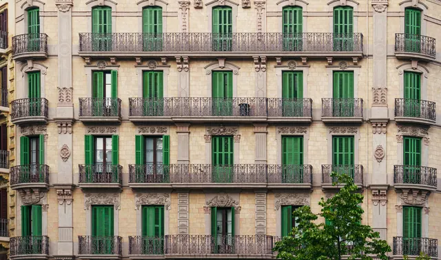 Fachada de un edificio clásico con balcones y persianas verdes