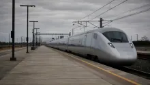 Tren de alta velocidad plateado detenido en andén de estación ferroviaria