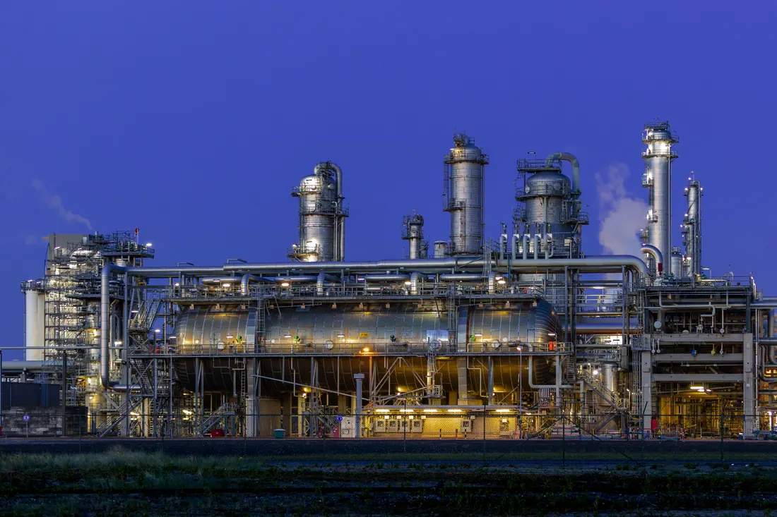 Tuberías y torres de una refinería industrial al atardecer