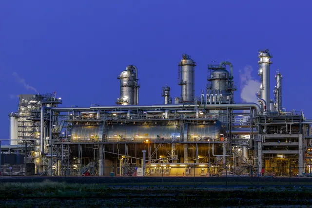 Tuberías y torres de una refinería industrial al atardecer