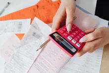 Manos usando una calculadora sobre tickets y facturas de papel