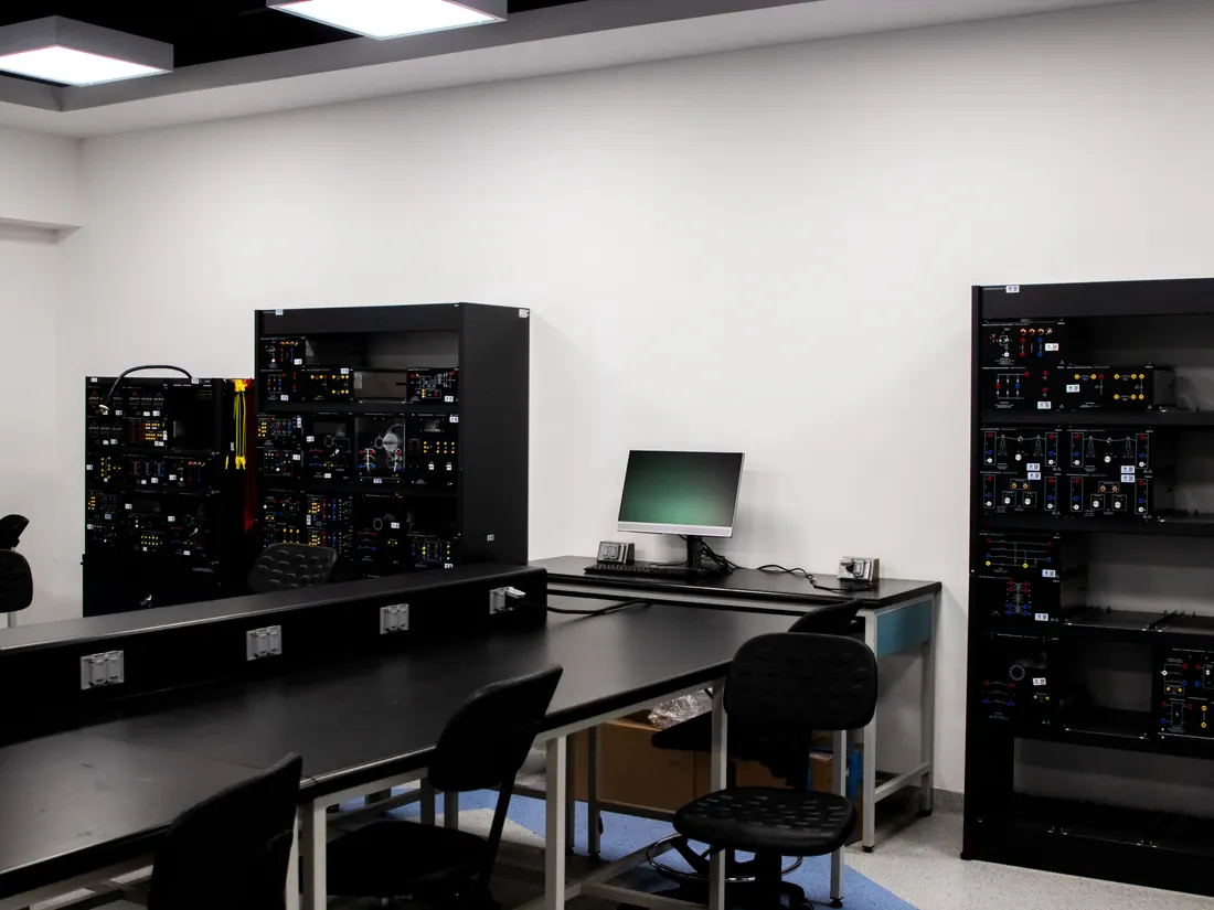 Laboratorio con racks de equipos electrónicos y estaciones de trabajo